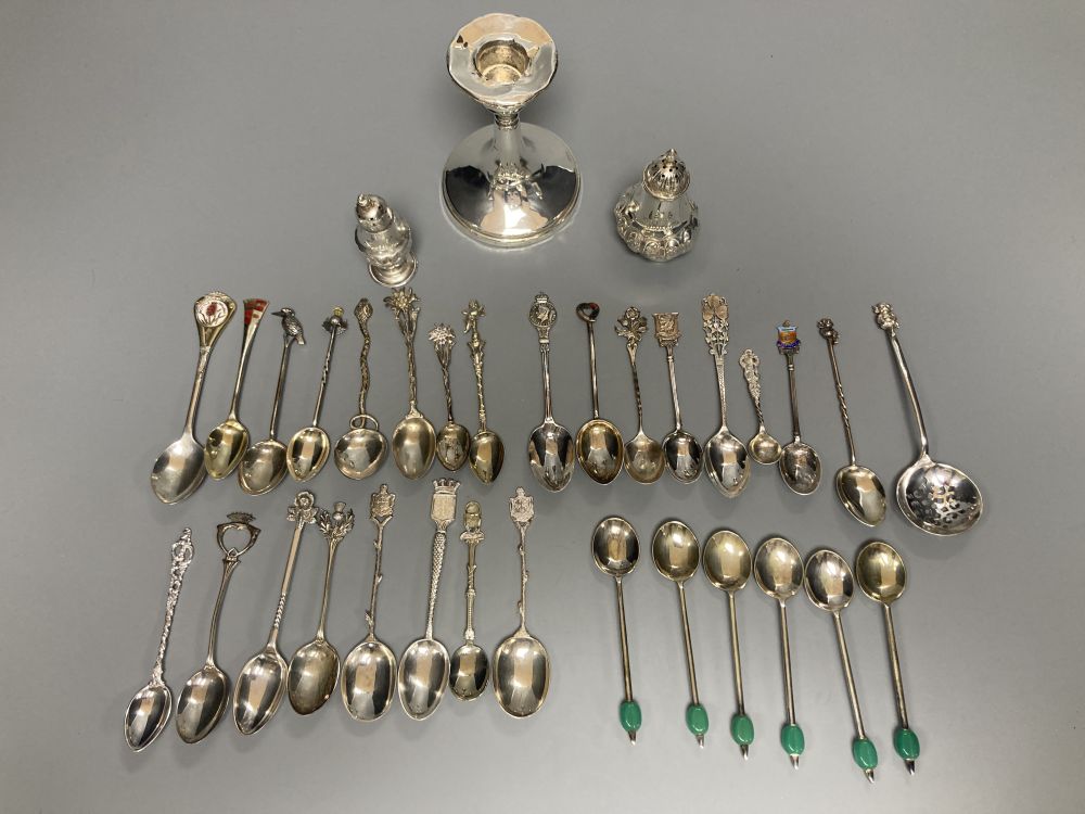 A silver dwarf candlestick, two silver condiments and a group of assorted silver, white metal and plated mainly commemorative spoons,